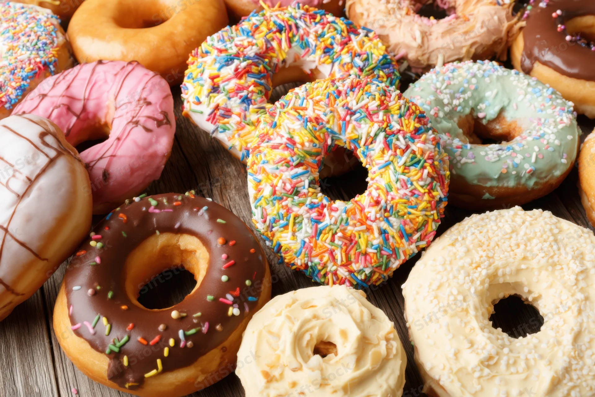 Colorful donuts with various frostings and sprinkles arranged on a wooden surface