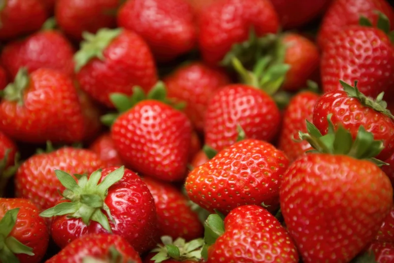 Closeup of fresh red strawberries with green stems arranged in a pile