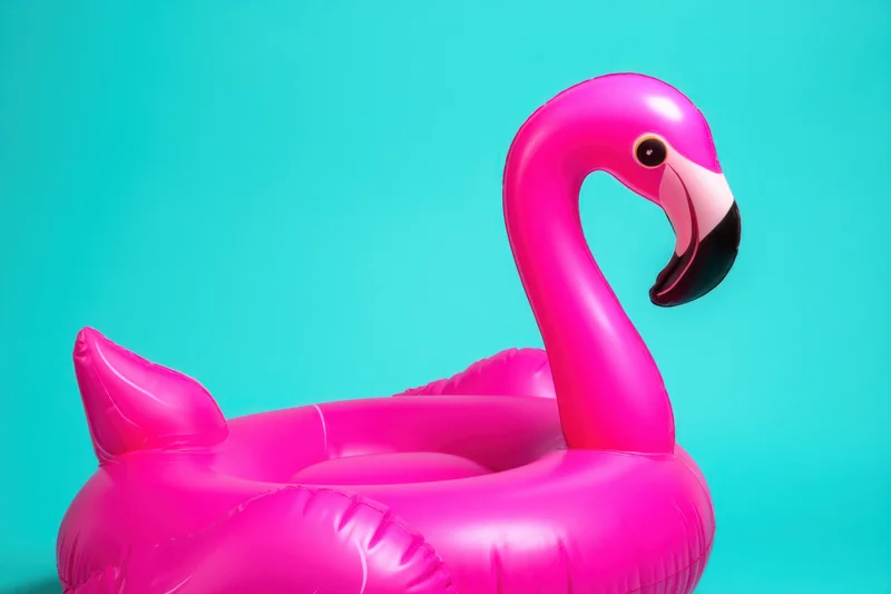 Inflatable pink flamingo float against turquoise background with copyspace