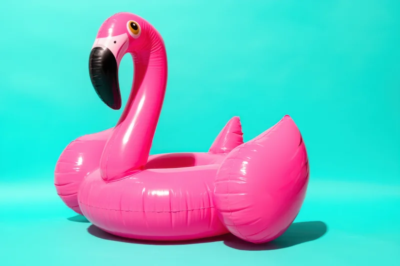 Inflatable pink flamingo float resting on a bright turquoise surface