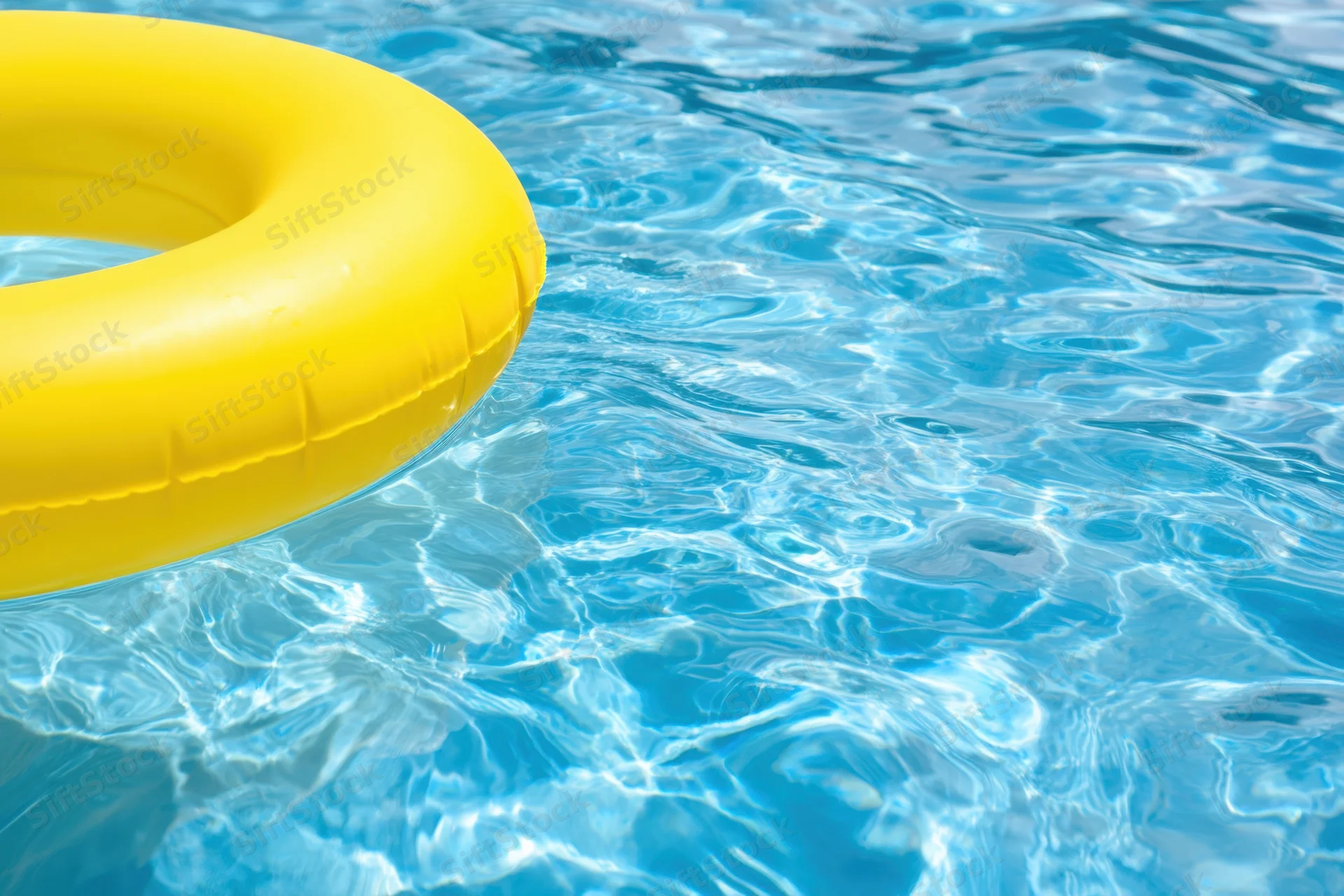 Yellow inflatable float bobbing in clear blue pool water