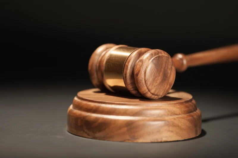 Wooden gavel resting on circular base illuminated against dark background