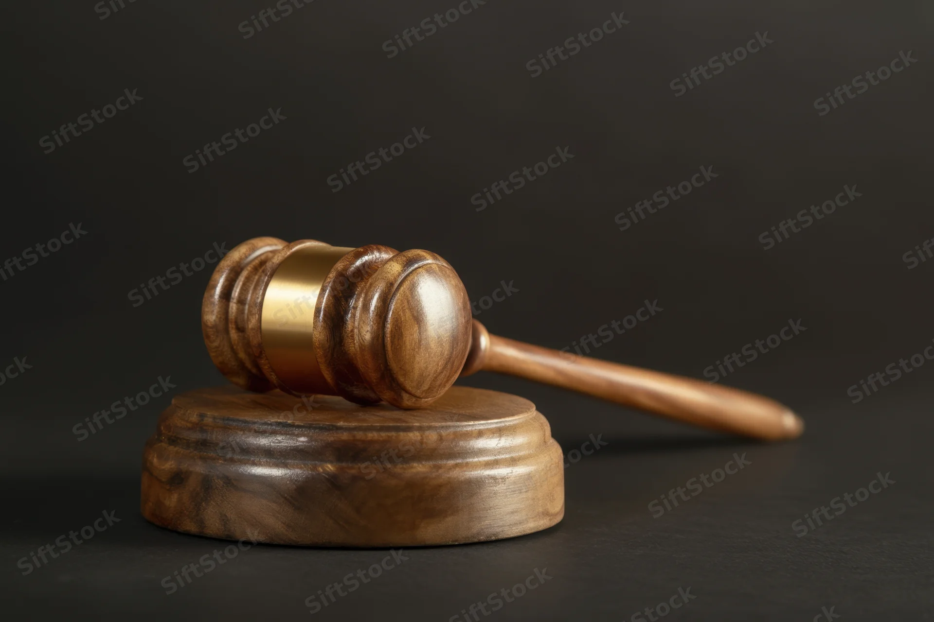 Wooden gavel resting on circular base against dark background