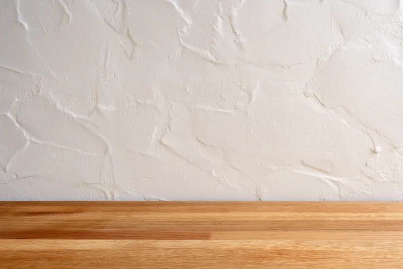 Wooden table with smooth natural finish against white textured wall