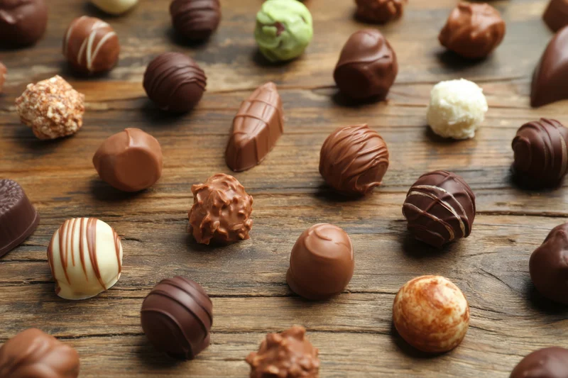 Assorted chocolate truffles scattered on a rustic wooden surface