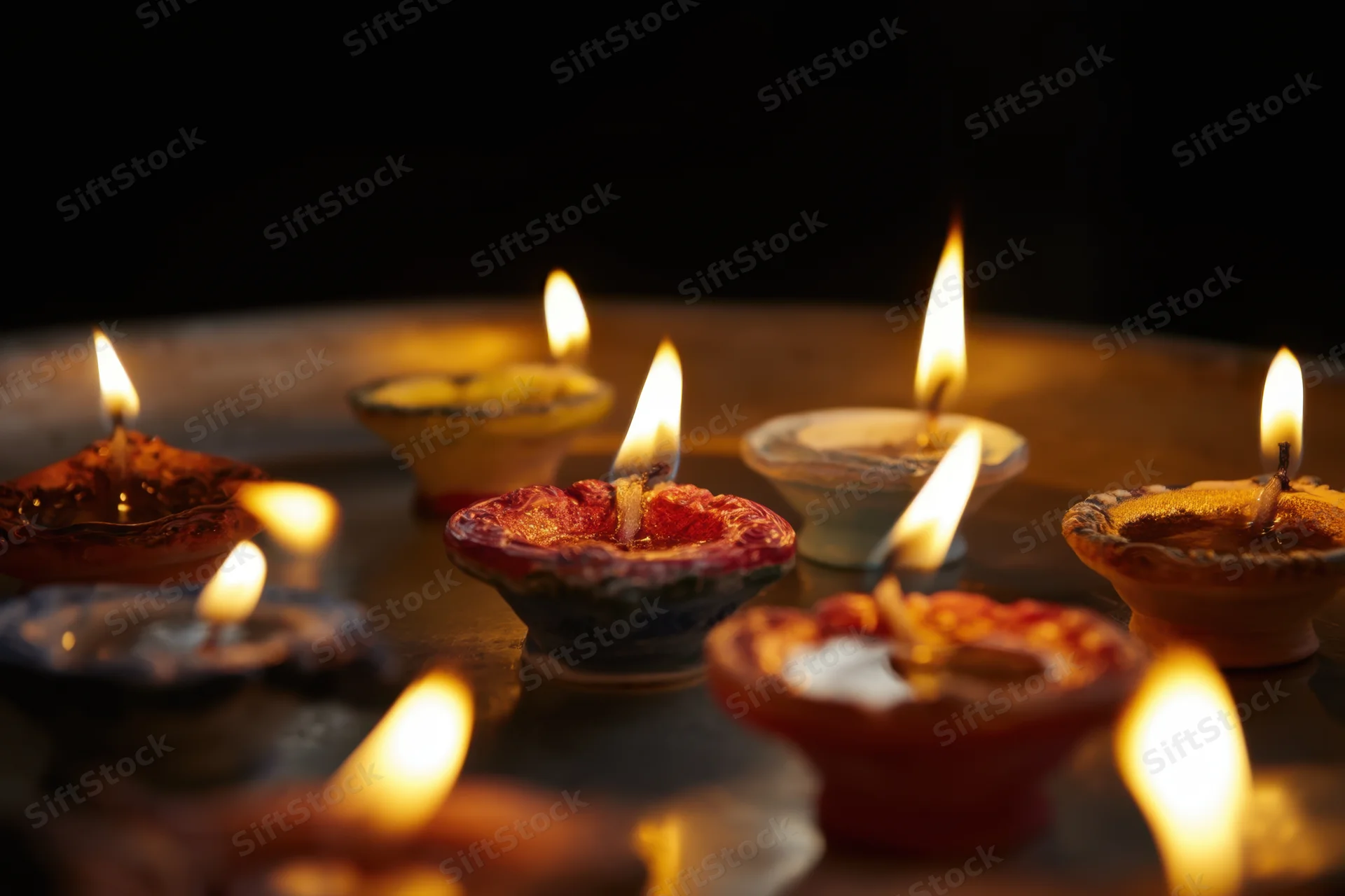 Traditional oil lamps glowing softly on a dark surface during a festive ritual