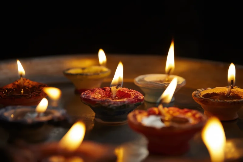 Traditional oil lamps glowing softly on a dark surface during a festive ritual