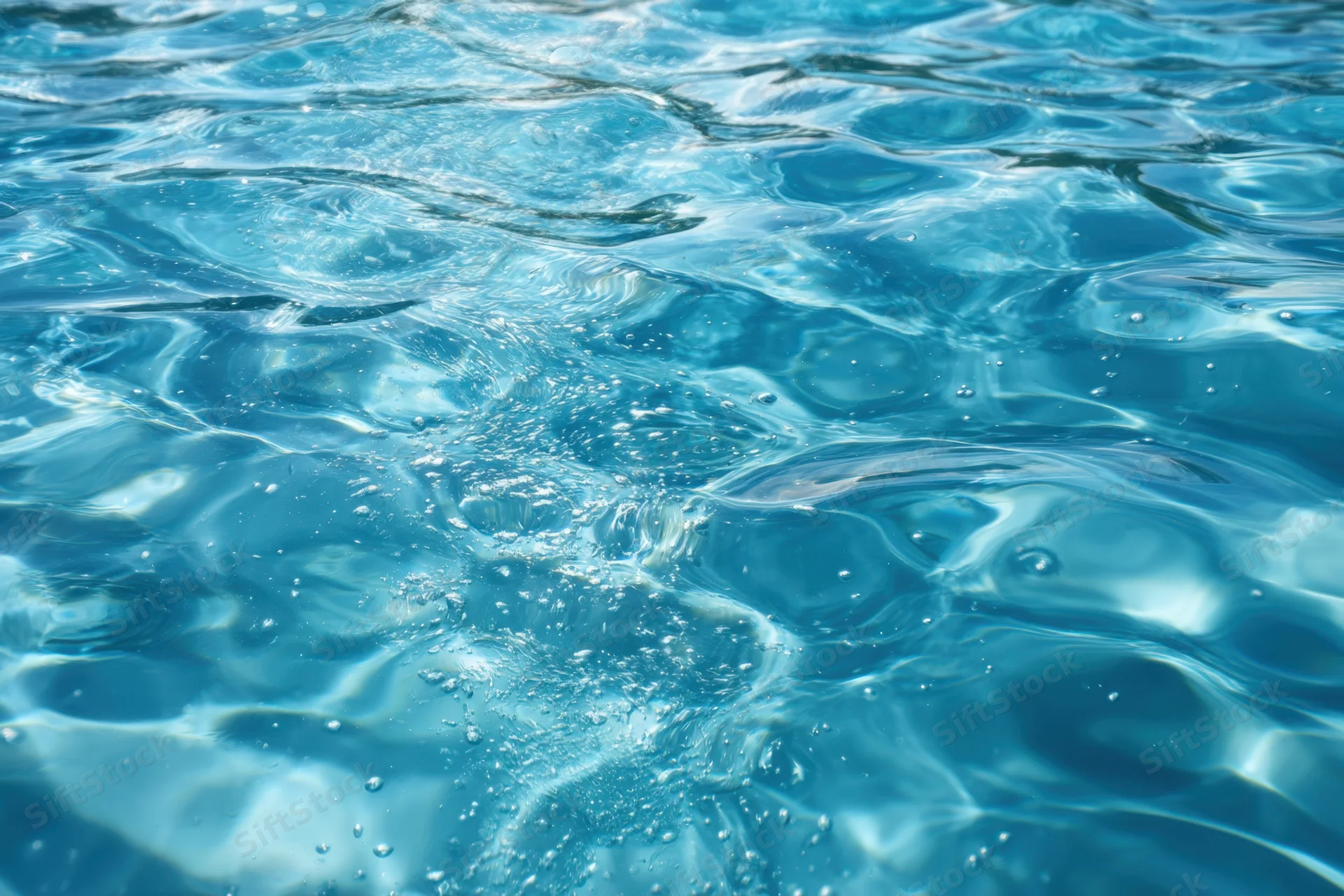 Clear blue water with ripples and bubbles on a sunlit surface