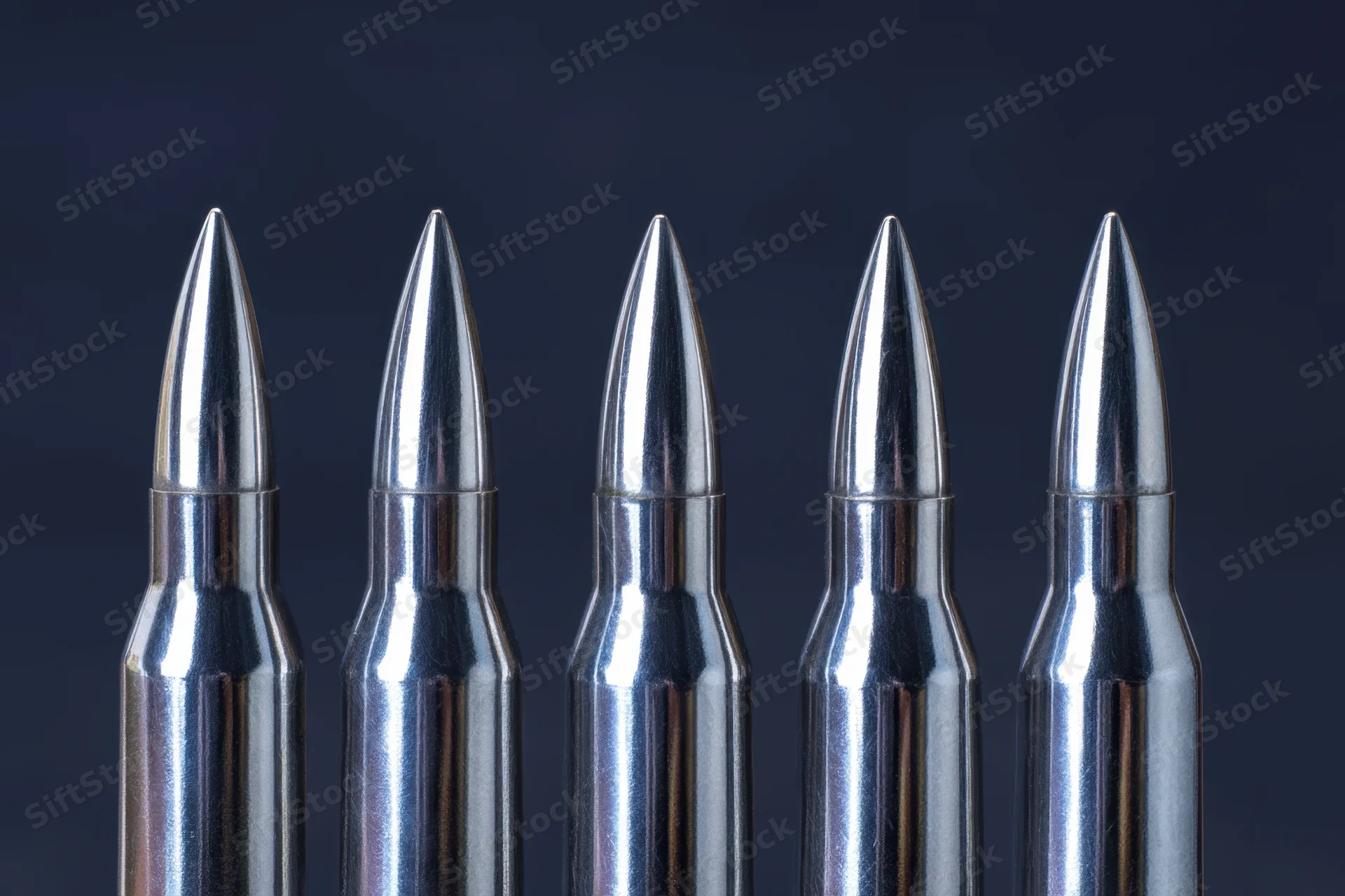 Five metallic bullets arranged in a row against a dark background