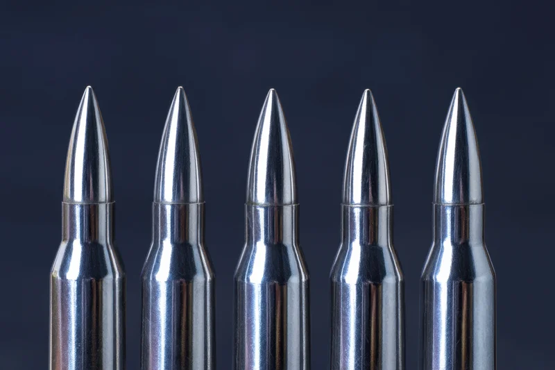 Five metallic bullets arranged in a row against a dark background