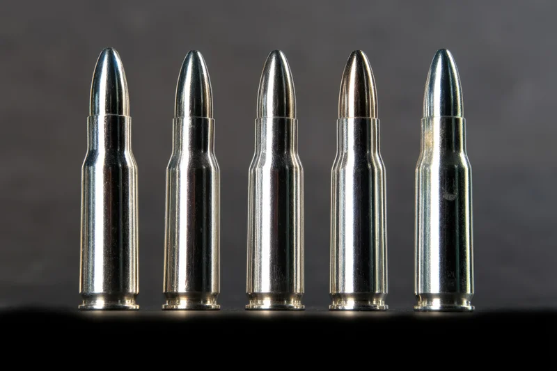 Five metallic bullets arranged in a row against a dark background