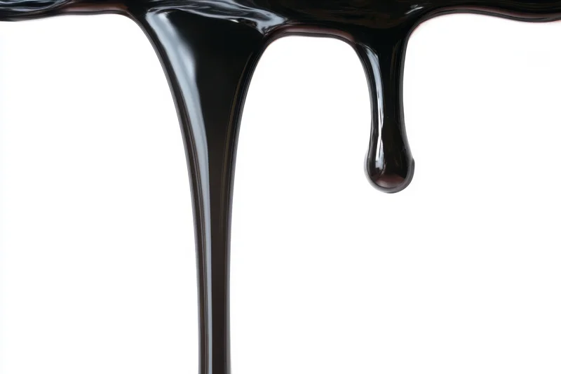Glossy black paint dripping down against a stark white background