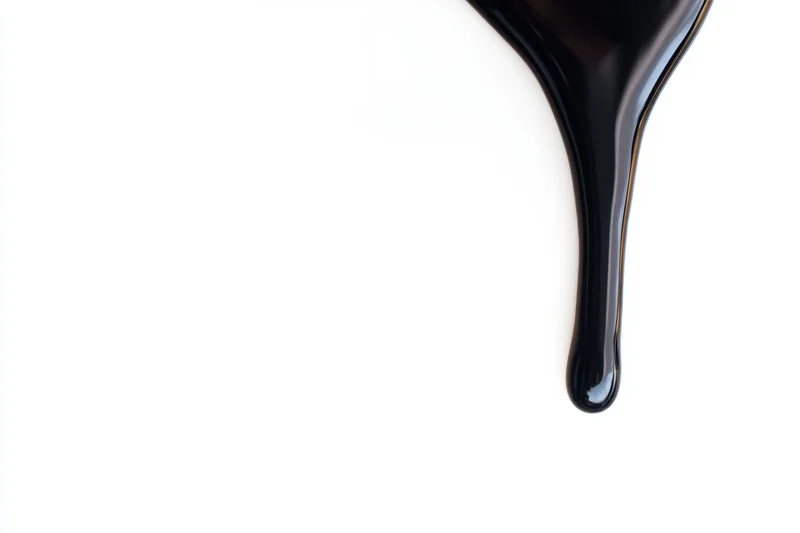 Glossy black paint dripping down against a stark white background