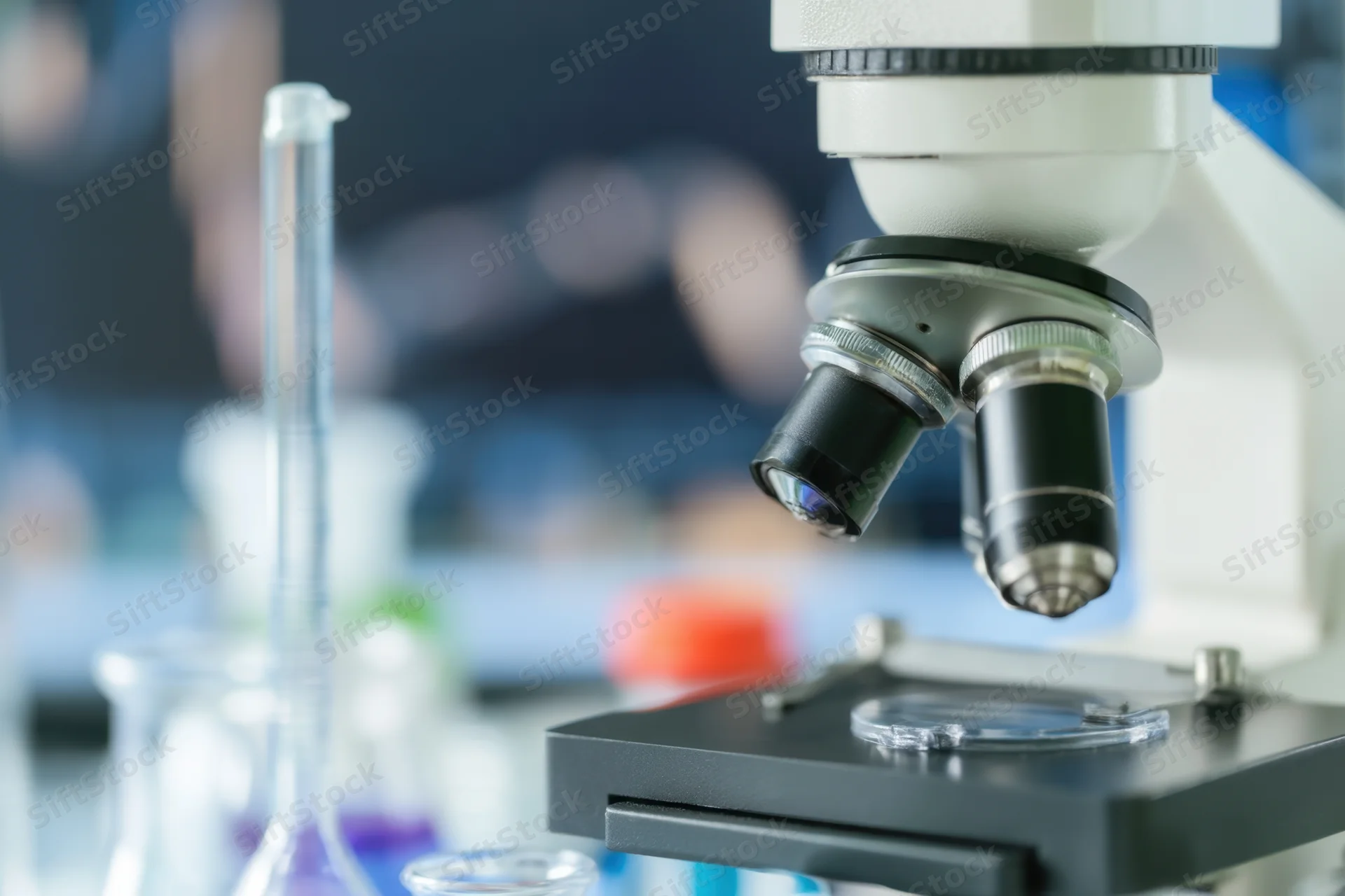 Close-up of a microscope with glassware on a laboratory bench