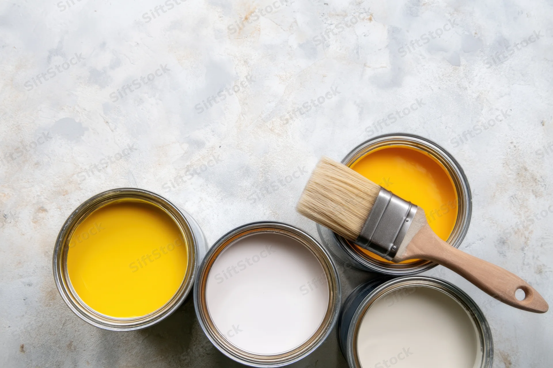 Open paint cans with a brush arranged on a textured gray surface