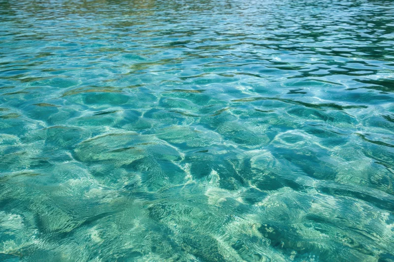 Turquoise water with gentle ripples and reflections on a calm surface