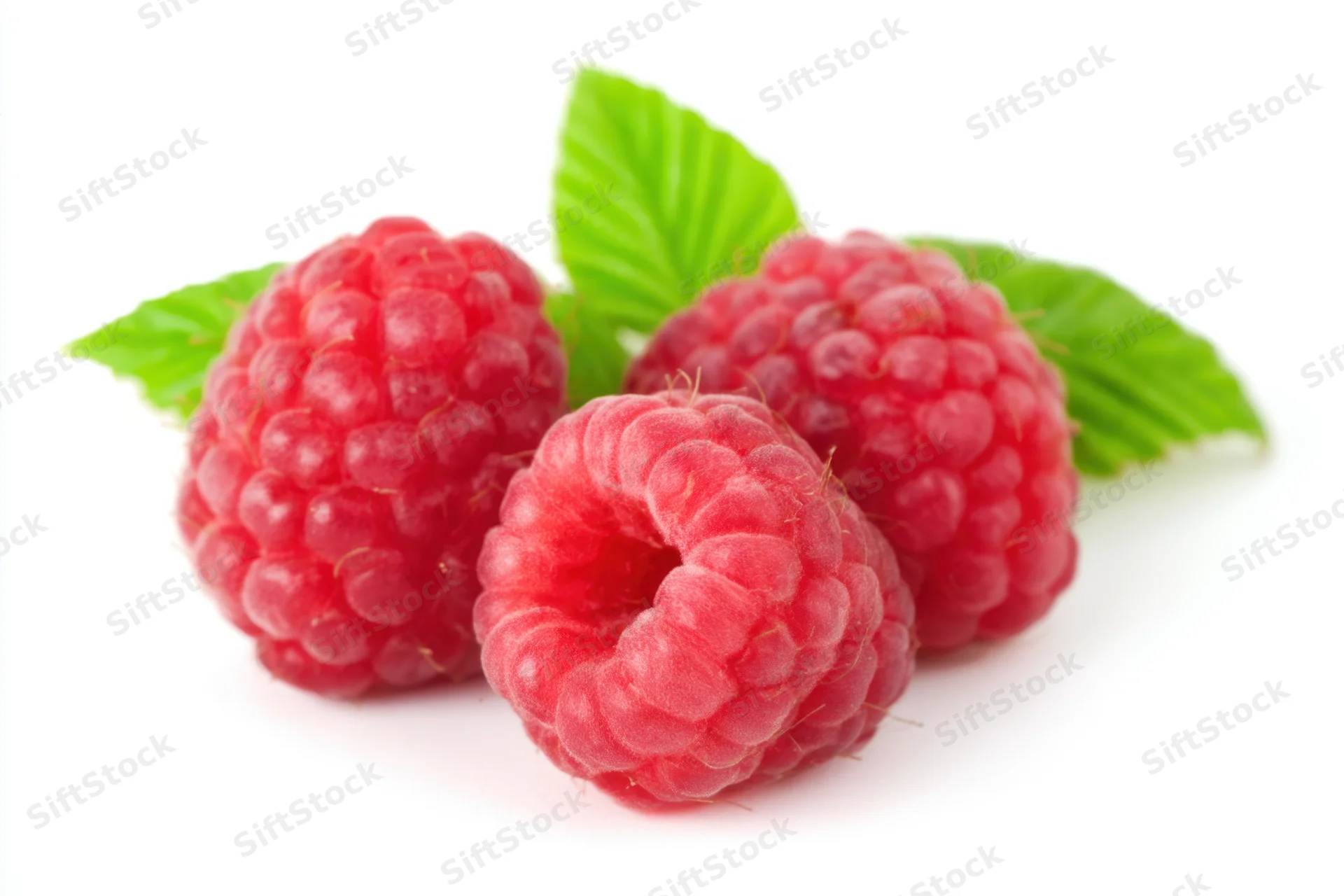Three plump red raspberries with green leaves on white background