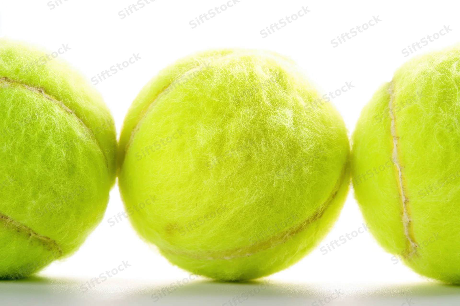 Three tennis balls arranged in a row on a white surface