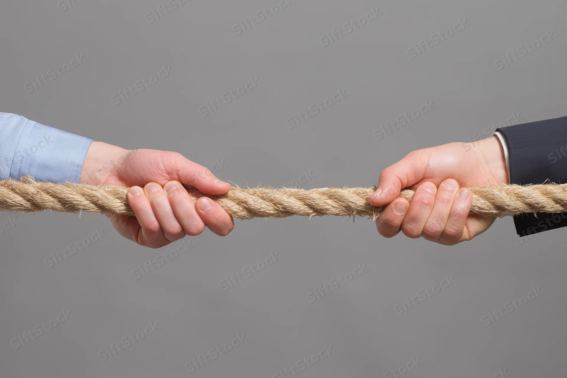 Two hands gripping a rope in a tug-of-war against a gray background