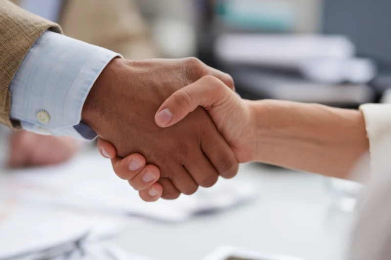 Two people shaking hands in an office setting during a professional meeting