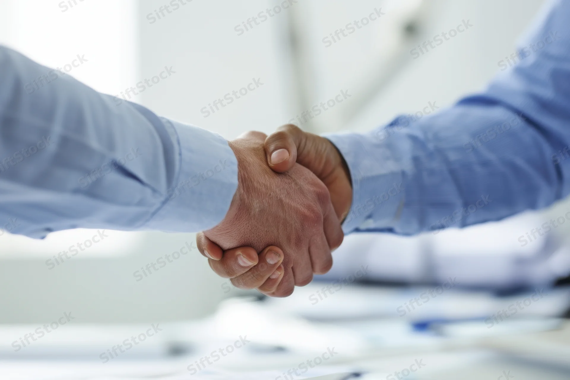 Two men shaking hands in an office setting during a business meeting