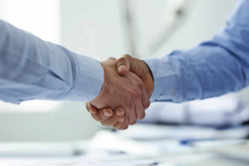 Two men shaking hands in an office setting during a business meeting