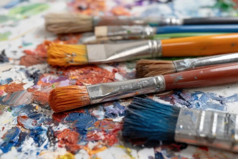 Paintbrushes resting on a colorful palette with dried paint smudges