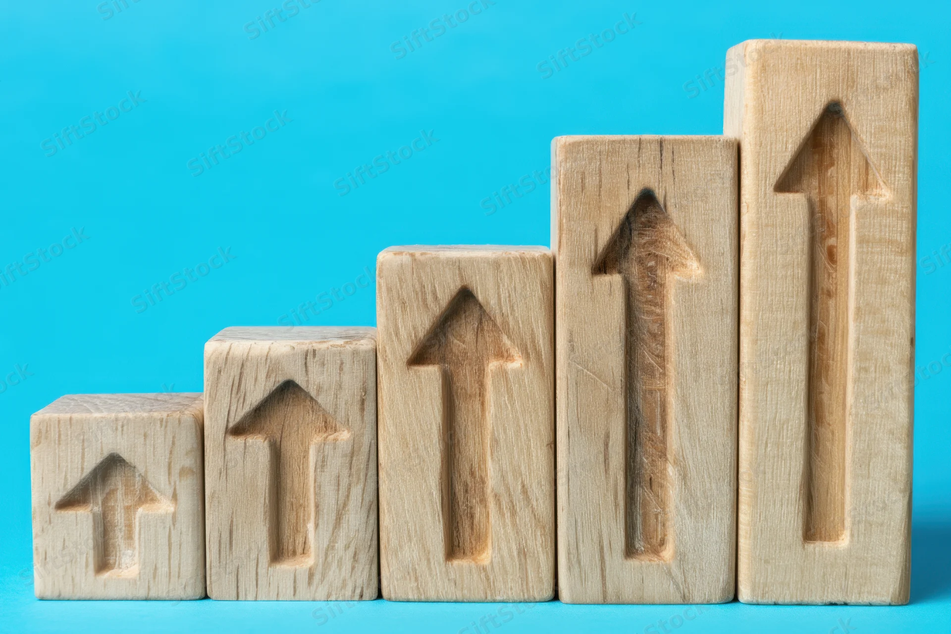 Wooden blocks with carved arrows arranged in ascending order on a blue background