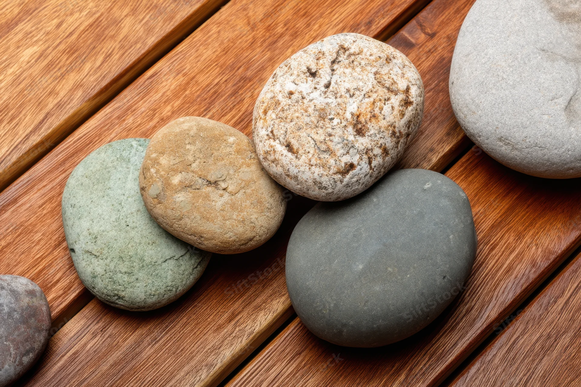 Smooth rounded stones arranged on a warm wooden deck surface