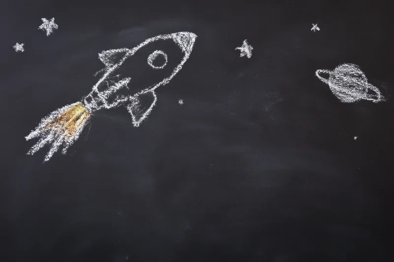 Chalk drawing of a rocket ship launching into space on a blackboard