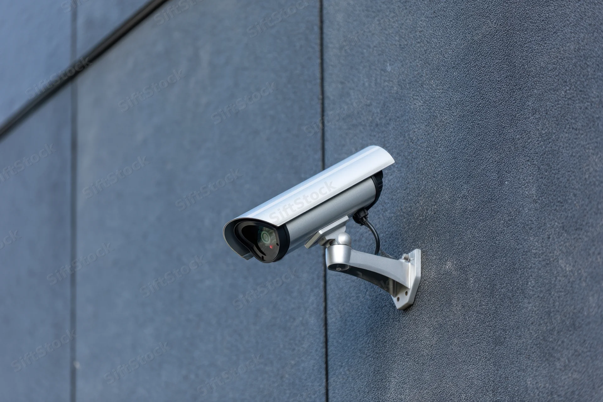 Cctv camera mounted on textured dark gray wall exterior
