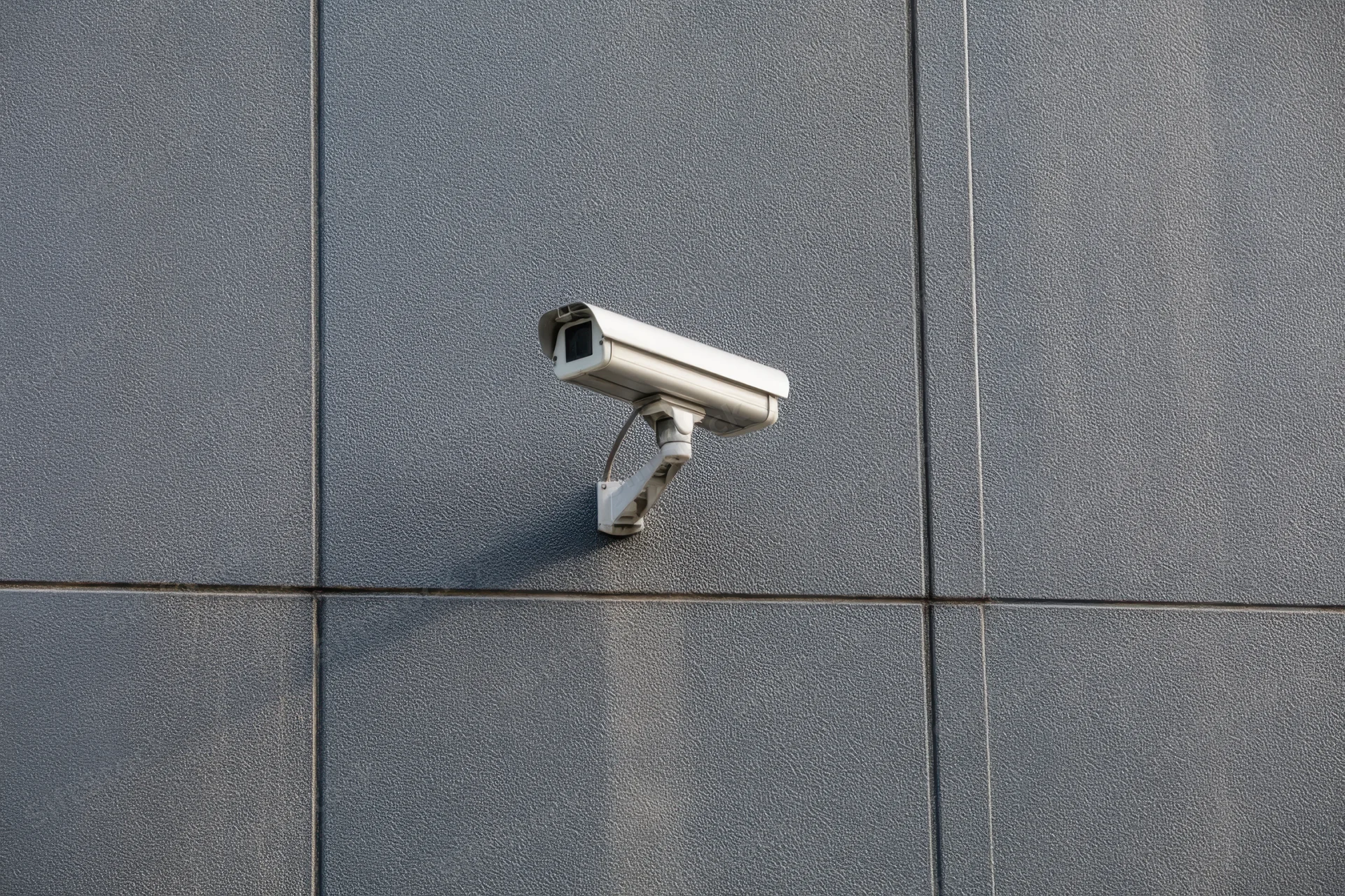 Cctv camera mounted on textured dark gray wall exterior