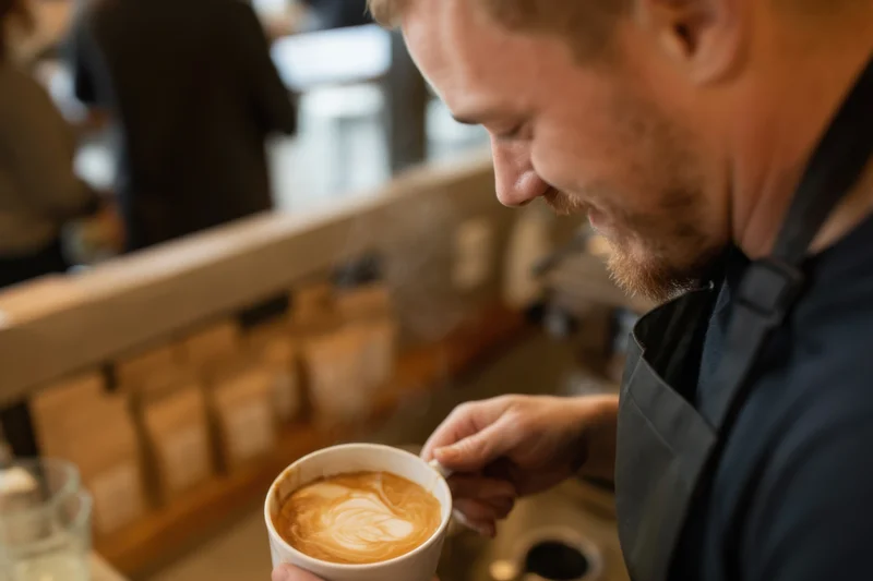Barista pouring steamed milk into a latte cup at a coffee shop counter