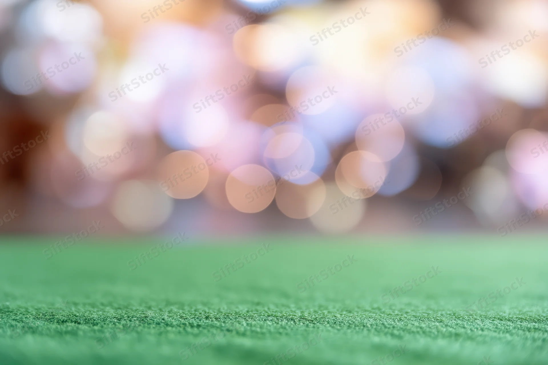 Green artificial turf field with blurred bokeh lights in the background