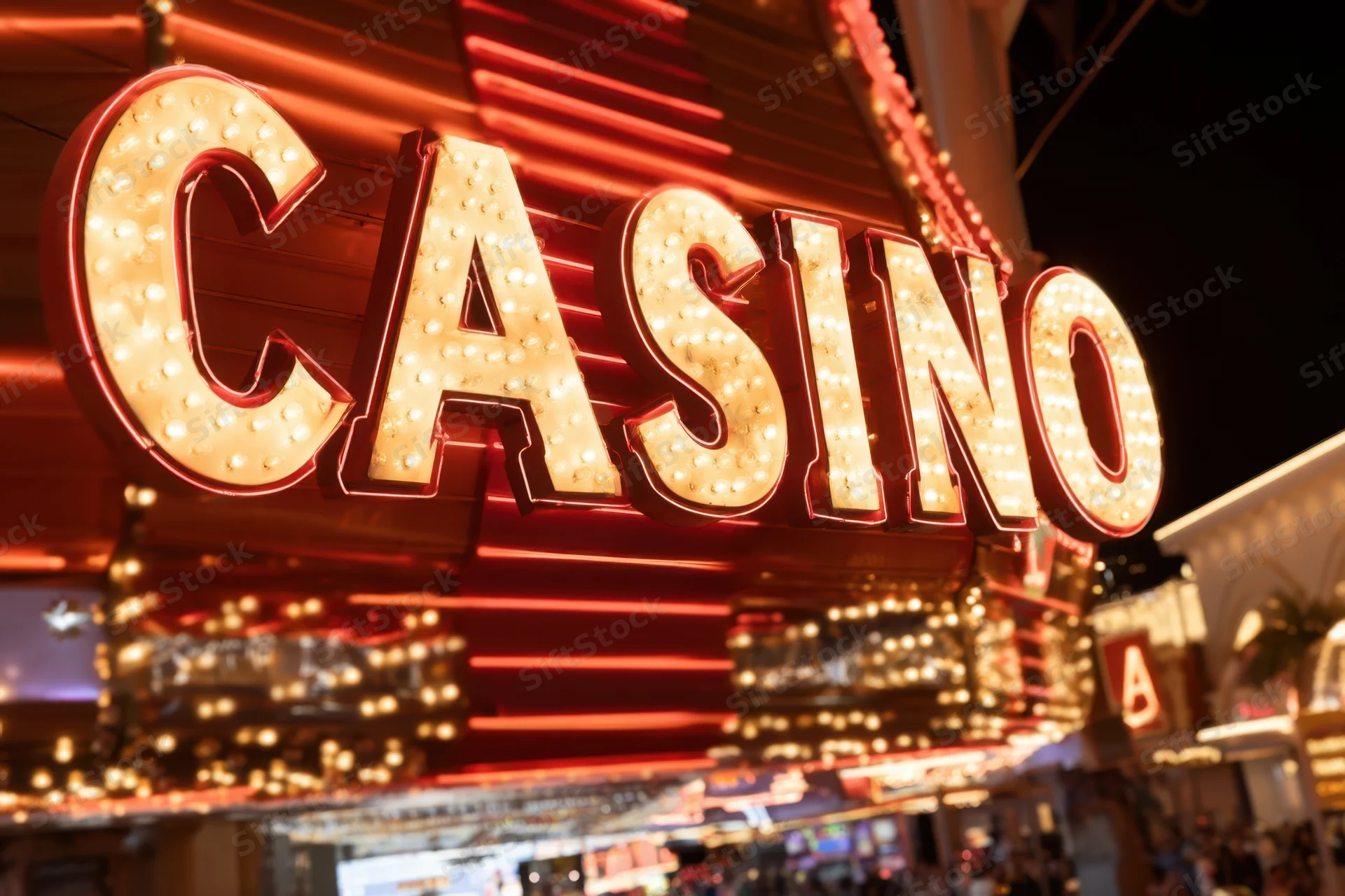 Brightly illuminated casino sign with bold lettering and glowing bulbs on a city building exterior at night