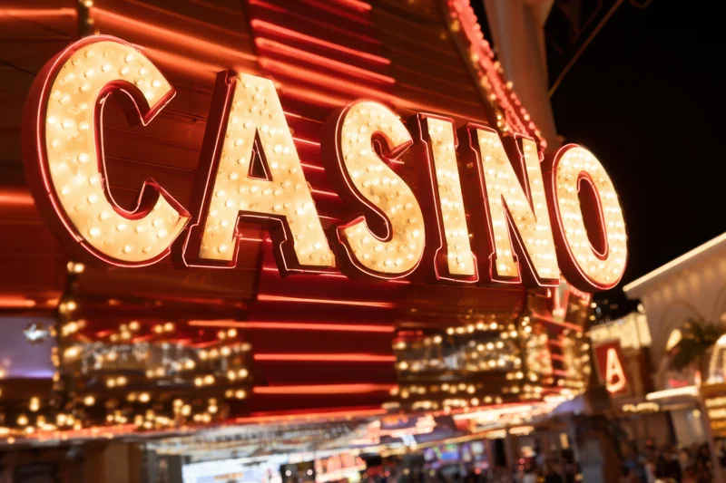 Brightly illuminated casino sign with bold lettering and glowing bulbs on a city building exterior at night