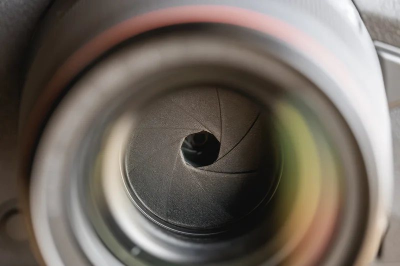 Closeup view of a camera lens aperture with visible blades arranged in a circular pattern