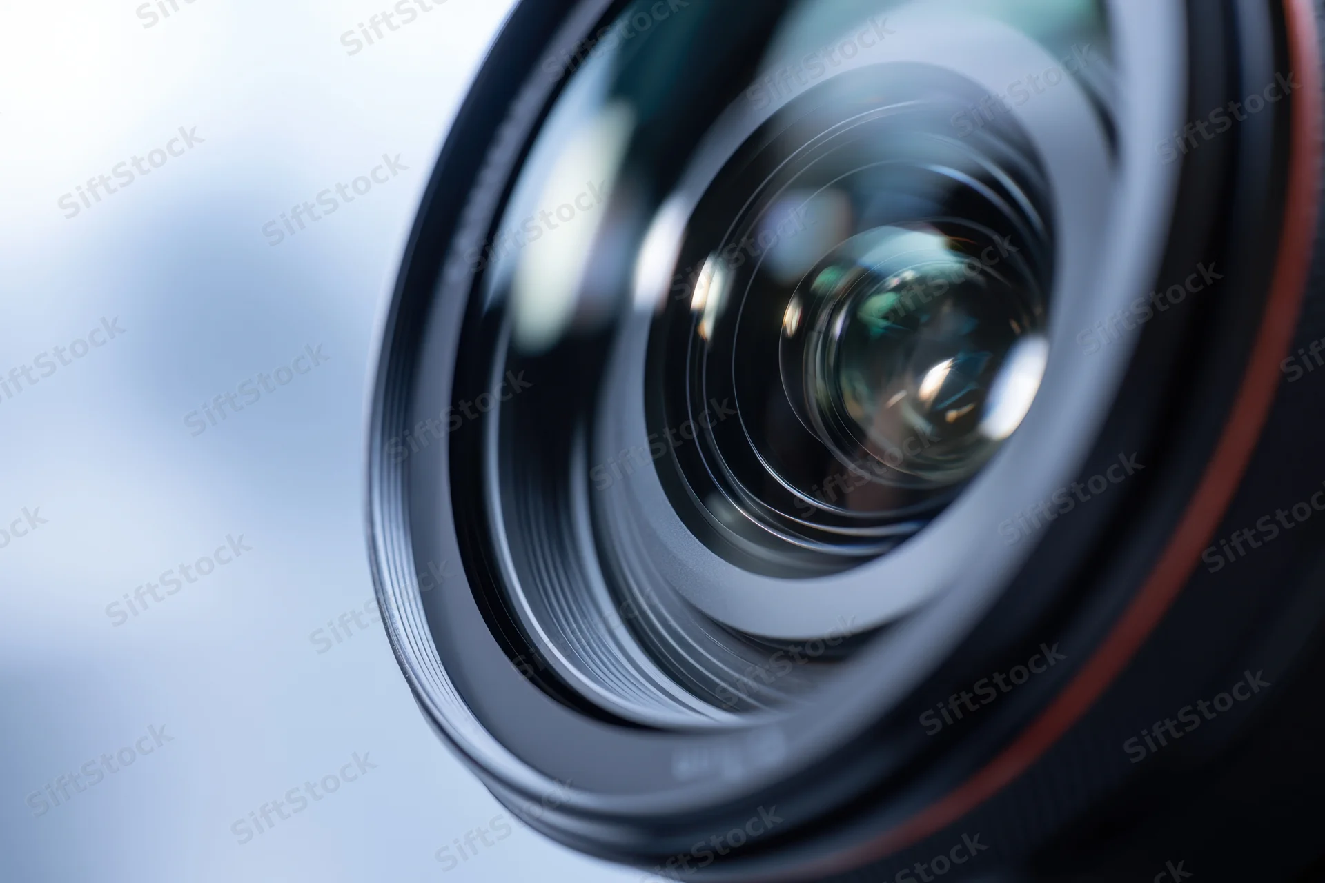 Closeup of a camera lens showing intricate glass elements and reflections with a blurred background