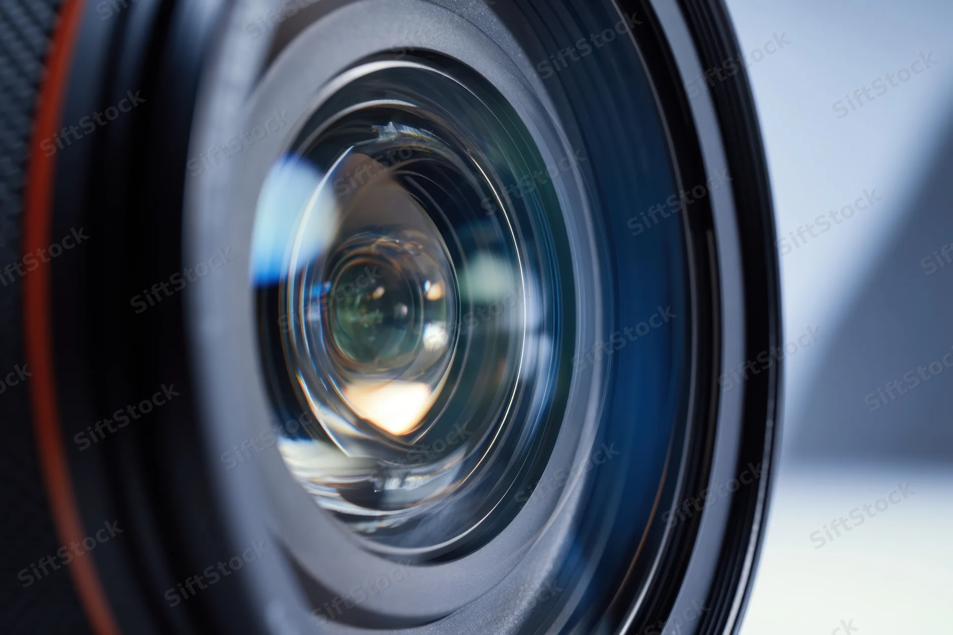 Closeup of a camera lens showing intricate glass elements and reflections in the aperture