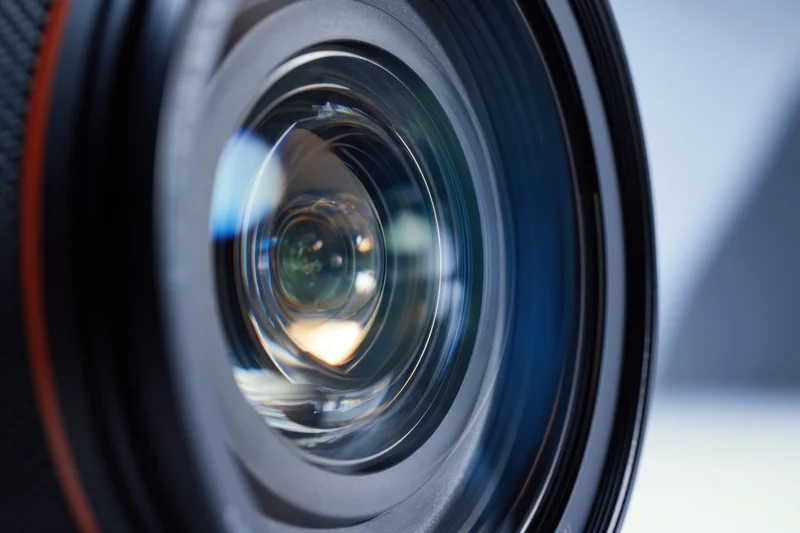 Closeup of a camera lens showing intricate glass elements and reflections in the aperture
