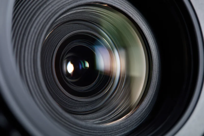Closeup of a camera lens showing intricate glass elements and reflective surfaces in a detailed view