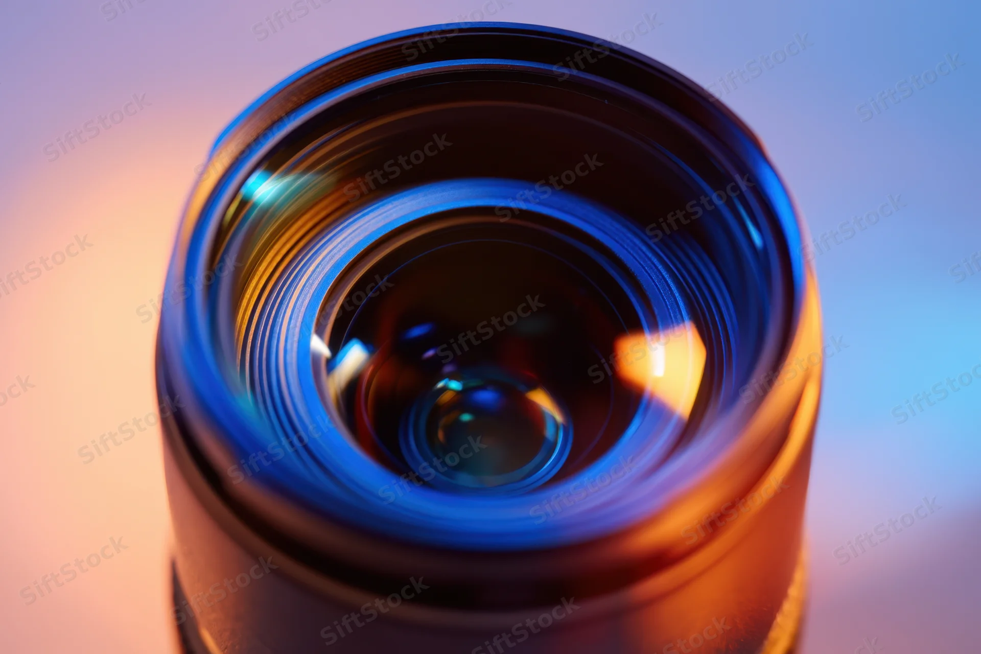 Closeup of a camera lens showing concentric glass elements with blue and orange light reflections