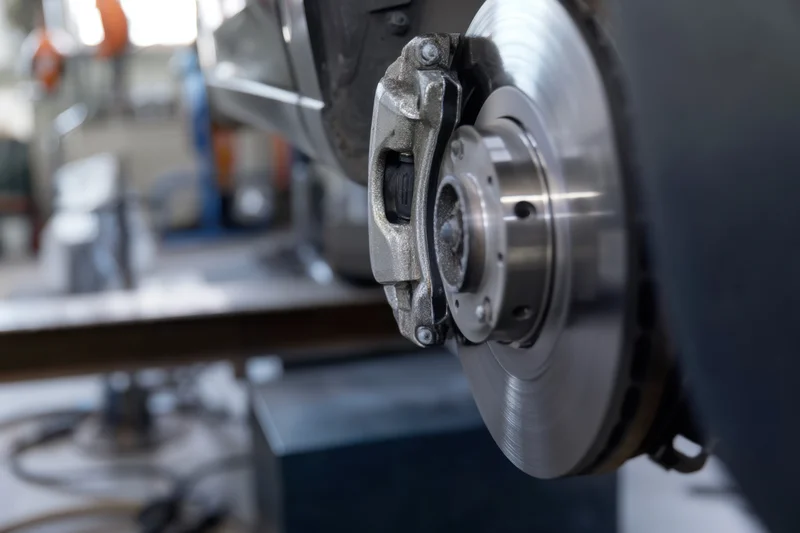 Closeup of a car brake disc and caliper during inspection in a workshop