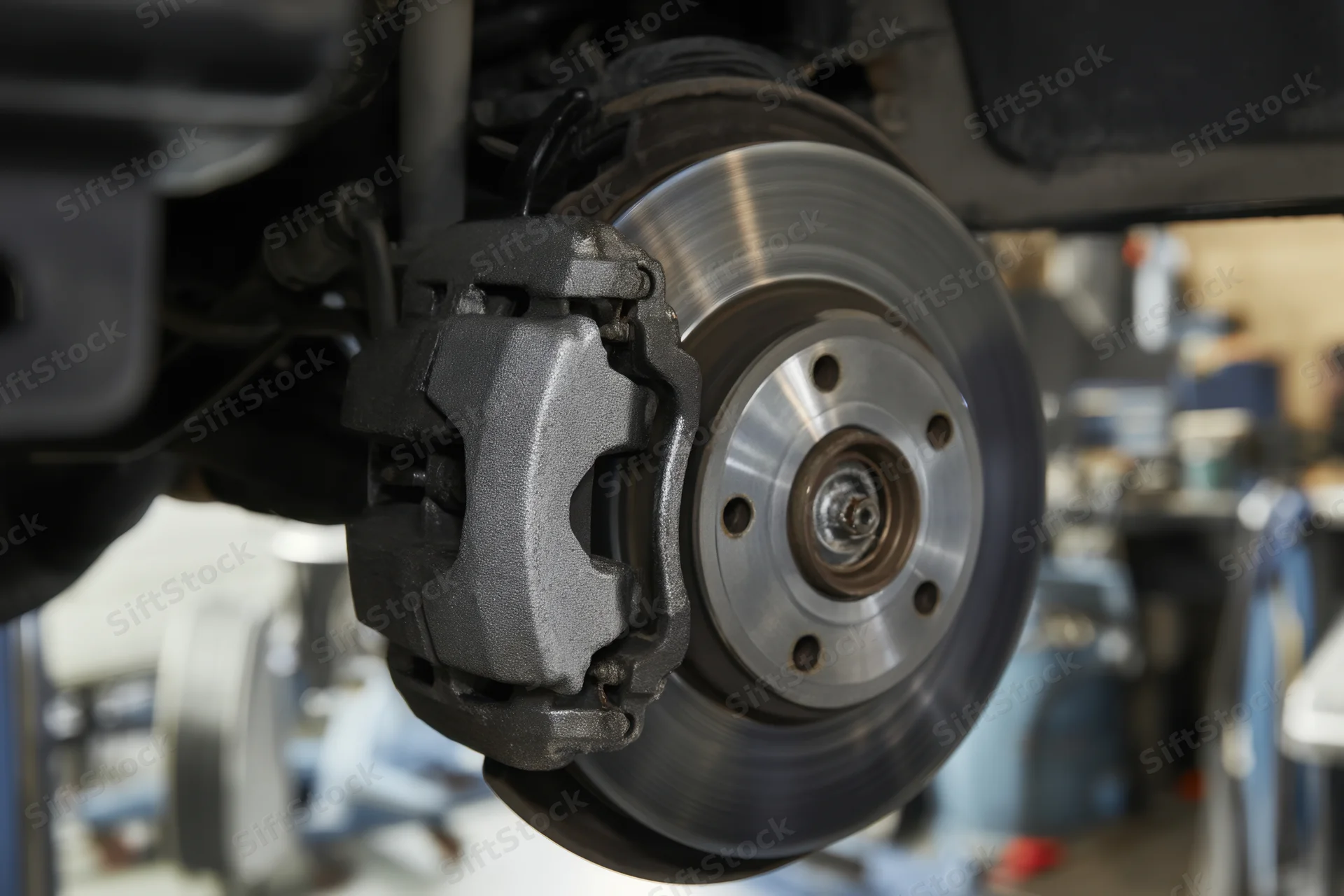 Closeup of car brake disc and caliper during inspection in a workshop