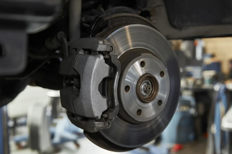 Closeup of car brake disc and caliper during inspection in a workshop