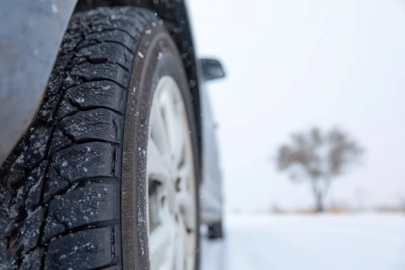 Close-up of a car tire with snow in the tread on a snowy road