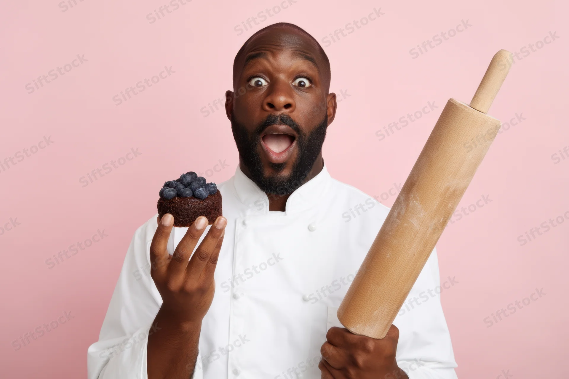 Baker in white coat holding blueberry cake and rolling pin against pink background