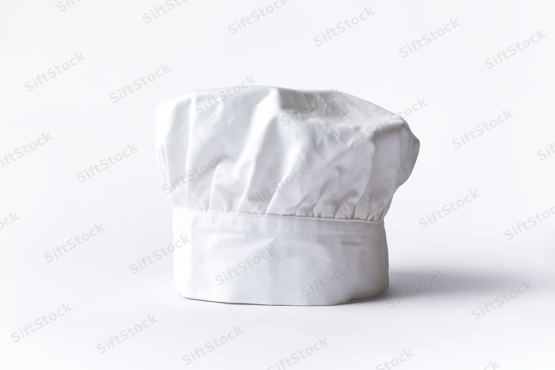 White chef hat made of soft fabric standing alone on a plain white surface