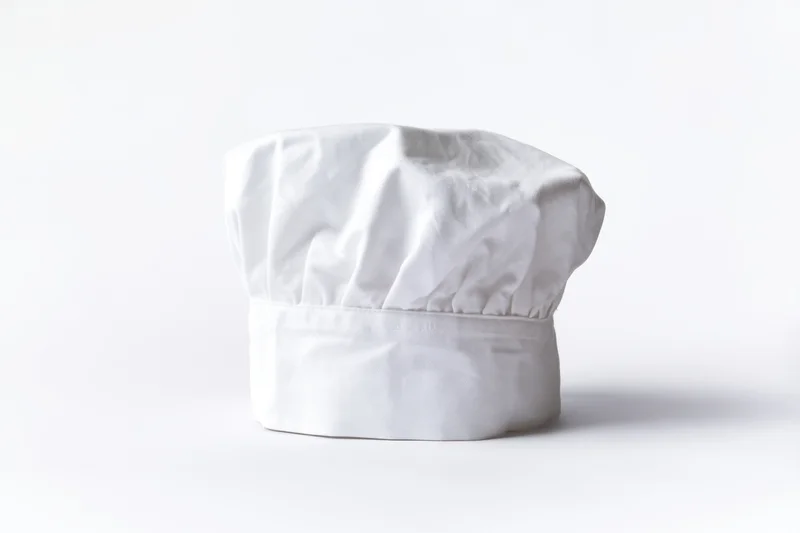 White chef hat made of soft fabric standing alone on a plain white surface