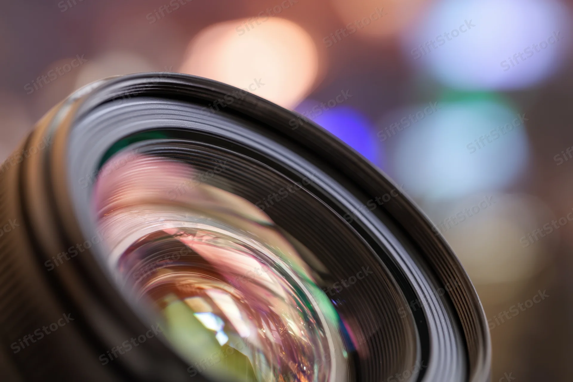 Close-up of a camera lens showing multi-colored reflections with blurred bokeh background